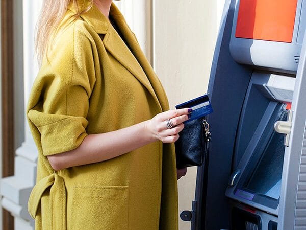 Woman using an ATM in Europe, one of the best ways to get money out in Europe with a good exchange rate! #travel #europe #money
