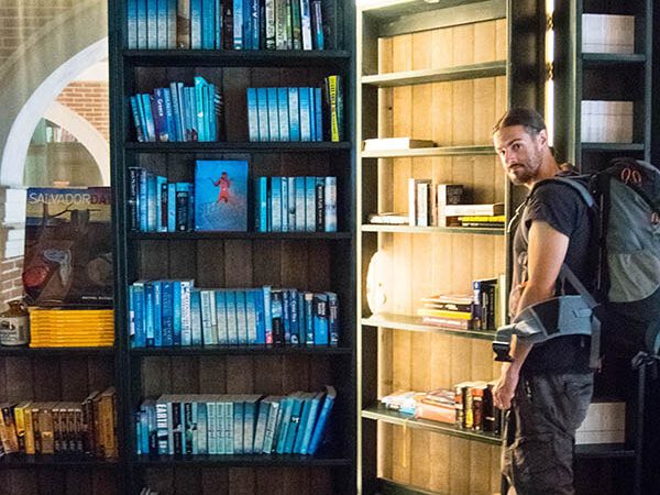 Man standing outside of a hotel room hidden within a bookshelf at Hotel Not Hotel In Amsterdam, a budget hotel in Amsterdam #amsterdam #hotels #hollland