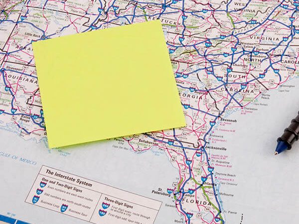 Person planning a first time road trip through the United States using an old school atlas with map of the United States open.