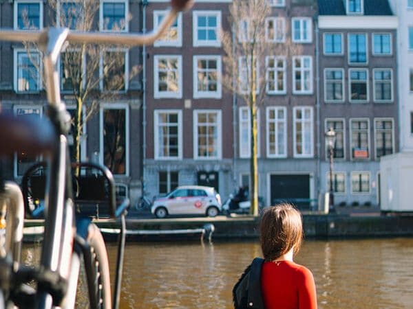 Girl enjoying solo travel in Amsterdam while sitting along Amsterdam canals!